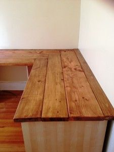 a wooden bench sitting on top of a hard wood floor next to a white wall