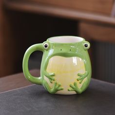 a green frog mug sitting on top of a table