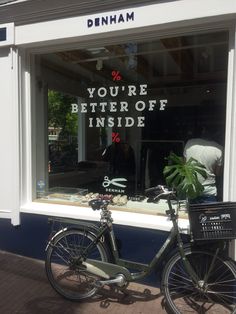 a bicycle parked in front of a store window with the words you're better off inside