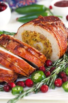 meatloaf with cranberry sauce and herbs on a white platter surrounded by holiday greenery