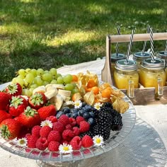 a platter of fruit is sitting on a table with mason jars and strawberries