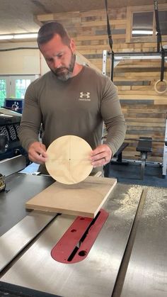 a man standing in front of a table with a piece of wood on it and another person behind him