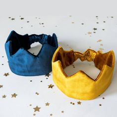 two blue and yellow crowns sitting on top of a white table covered in gold stars