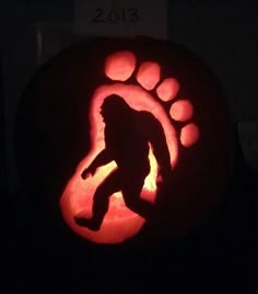 a pumpkin carved to look like a bigfoot with paw prints in the shape of a bear