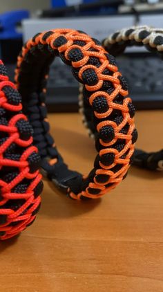 two black and orange bracelets sitting on top of a wooden table