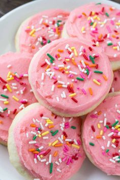 pink frosted cookies with sprinkles on a white plate