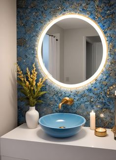 a bathroom sink with a blue bowl under a round mirror next to a candle and vase