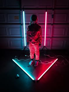 a person standing in front of two neon lights on a floor next to a garage door