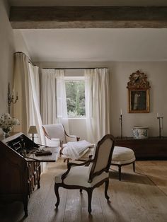 a living room filled with furniture next to a window covered in white curtained drapes