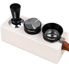 an image of a coffee maker and grinder set up on a white block with wood handle