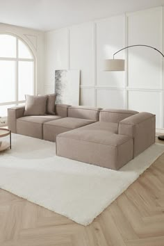 a living room filled with furniture on top of a hard wood floor covered in white rugs