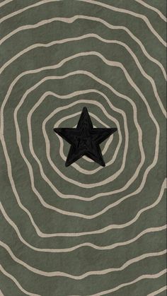 a black star sitting in the middle of a green and white swirly area with wavy lines