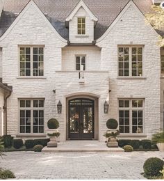 a large white brick house with lots of windows and plants on the front door area