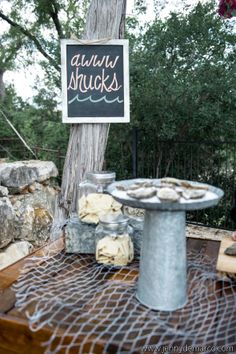 a sign that is on the side of a tree near some rocks and a birdbath