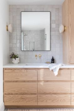 a bathroom with a large mirror above the sink and wooden cabinets on either side of it