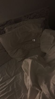 an unmade bed with white sheets and pillows