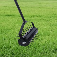 a large black rake sitting on top of a lush green field