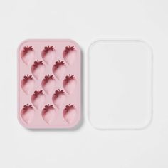 an ice tray with strawberries in the shape of hearts on it and a white background