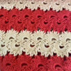 a red and white crocheted blanket with holes in the middle