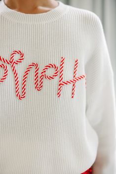 a woman wearing a white sweater with candy canes on the front and word hope written in red