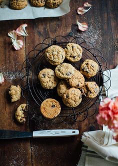 chocolate chip cookies are on a wire rack next to a knife and napkins with flowers in the background