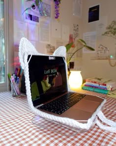 an open laptop computer sitting on top of a white and brown checkered table cloth