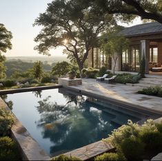 an outdoor pool surrounded by greenery and trees with the sun shining on it's horizon