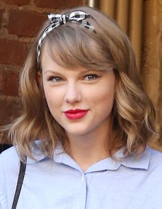 a close up of a person wearing a blue shirt with a bow in her hair