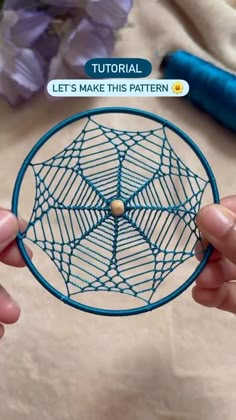 two hands holding up a small circular object with blue thread on it and the text, let's make this pattern