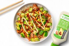 a white bowl filled with rice, avocado and carrots next to chopsticks