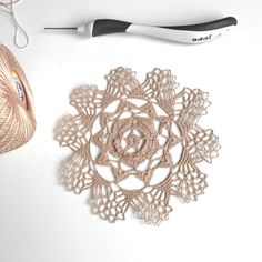 a crochet doily next to a ball of yarn and a pair of scissors