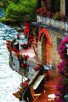 the balcony is decorated with flowers and potted plants next to the water's edge