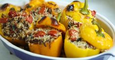 several stuffed peppers in a blue dish on a white counter top with other food items