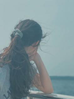 a woman with her hair blowing in the wind on a boat looking out at the ocean