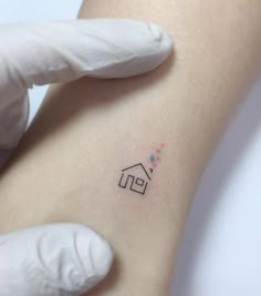 a small house tattoo on the back of a woman's left arm