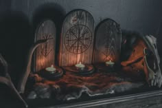 three wooden carvings sitting on top of a table next to candles and fur covered blankets