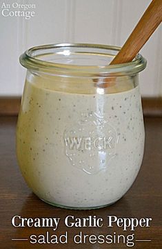 creamy garlic pepper salad dressing in a glass jar with a wooden spoon on the side