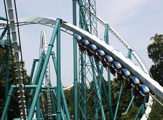 a roller coaster with several blue and white lights on it's side at an amusement park