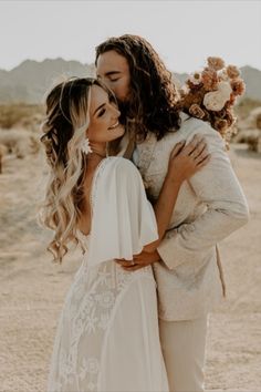 a couple embracing each other in the desert with flowers on their head and long hair