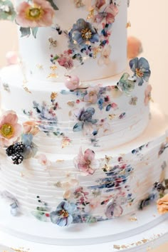 a three tiered white wedding cake with flowers on it