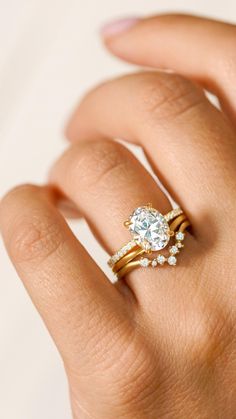 a woman's hand with a diamond ring on her finger and an engagement band