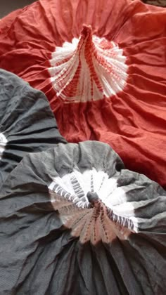 two red and black umbrellas sitting next to each other on top of a bed