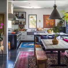 an open kitchen and dining room with rugs on the floor, potted plants in vases