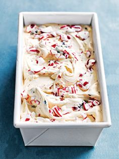 a square white dish filled with ice cream and candy canes on a blue surface