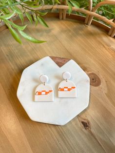 an orange and white earring sitting on top of a wooden table next to a potted plant