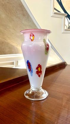 a glass vase sitting on top of a wooden table next to a bannister