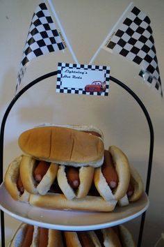 three hotdogs on buns with bun flags in the background and a checkered flag