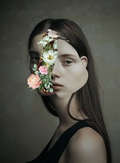 a woman with flowers in her hair is looking at the camera while she's wearing a black top