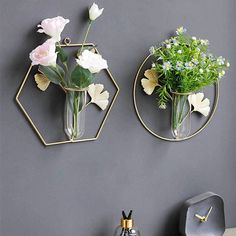 two vases with flowers are hanging on the wall