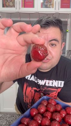 a man is holding up some strawberries in front of his face